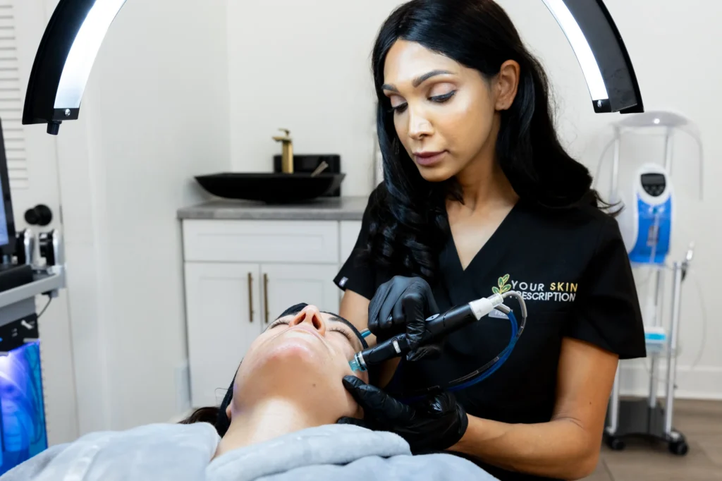 a doctor is performing a hydrafacial for skin care on a female patient